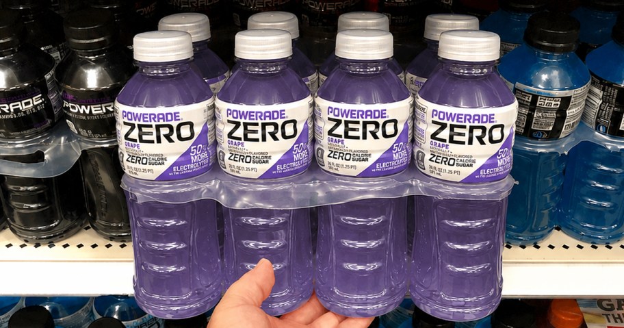 hand holding purple pack of Powerade Zero Sugar bottles in grocery store aisle