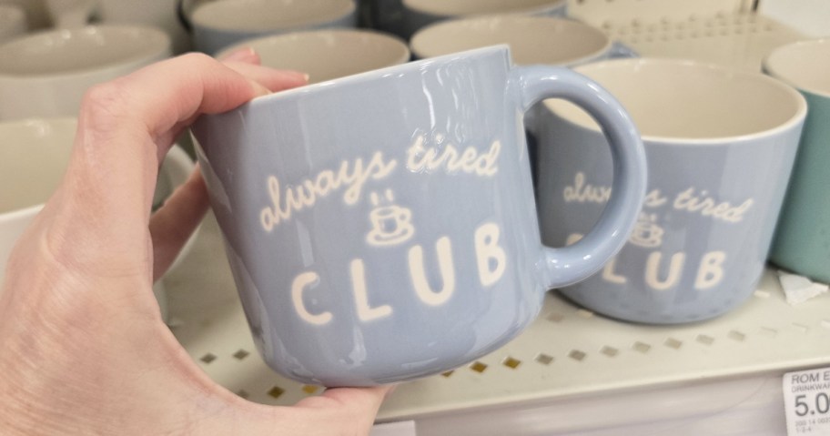 hand holding blue mug that says "Always Tired Club"