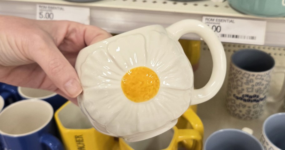 hand holding up a white flower mug
