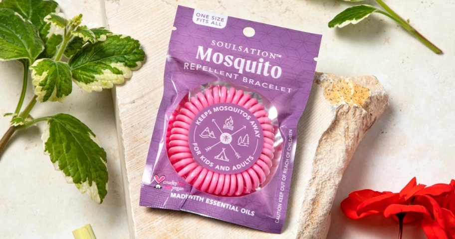Soulsation mosquito repellent bracelet with pink inner packaging surrounded by greenery 