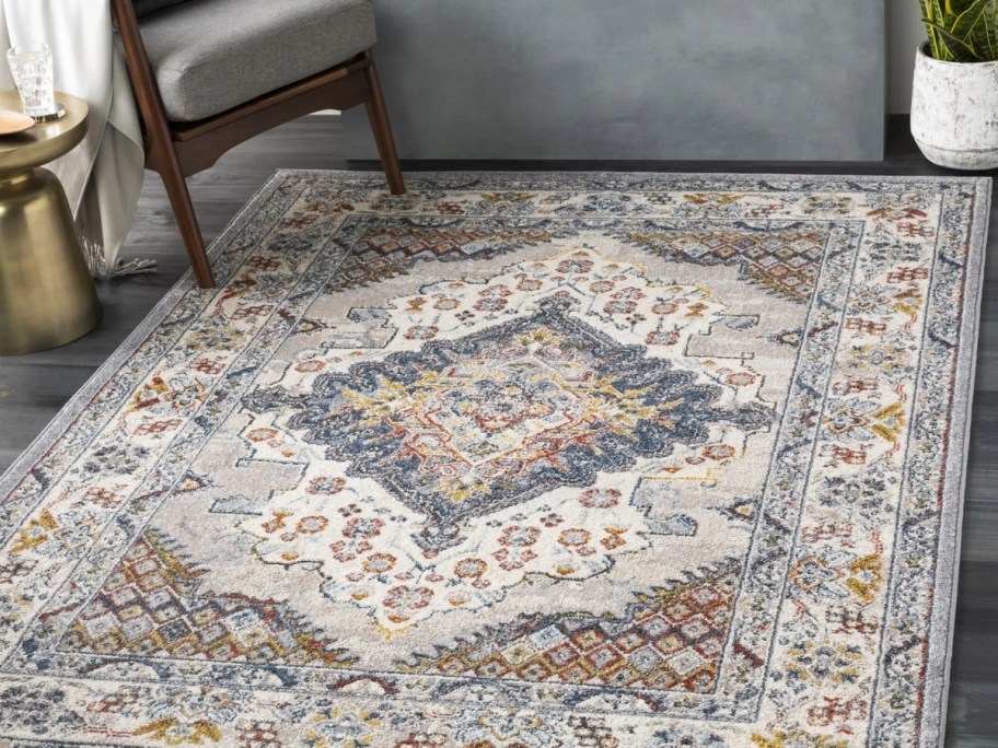 an oriental rug in shades of greey, orange, blue and gold