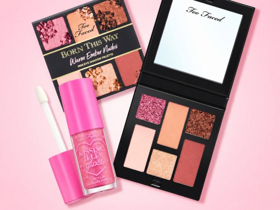 too faced eyeshadow palette and lip gloss on a pink background