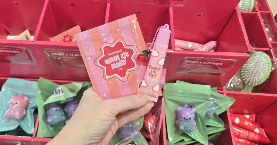 hand holding pink eye mask and lip balm in store