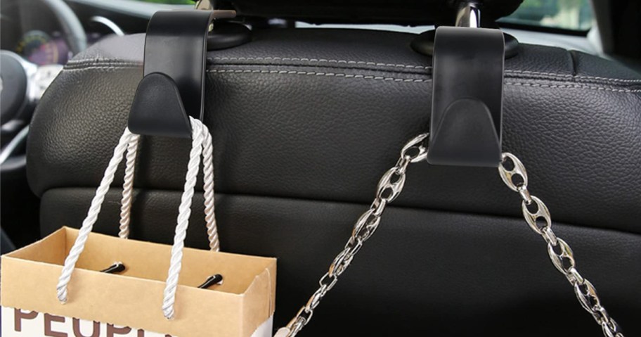 Car seat hooks holding a paper bag with rope handles and a chain accessory.