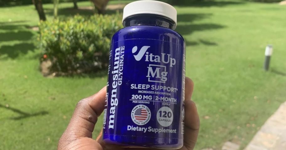 hand holding a bottle of VitaUp Mg capsules