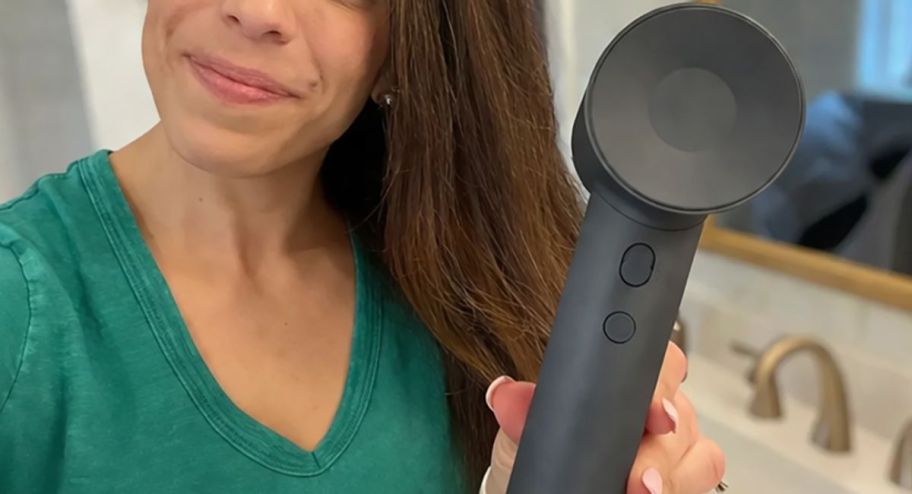 Woman wearing a green shirt holding a dark gray hari dryer