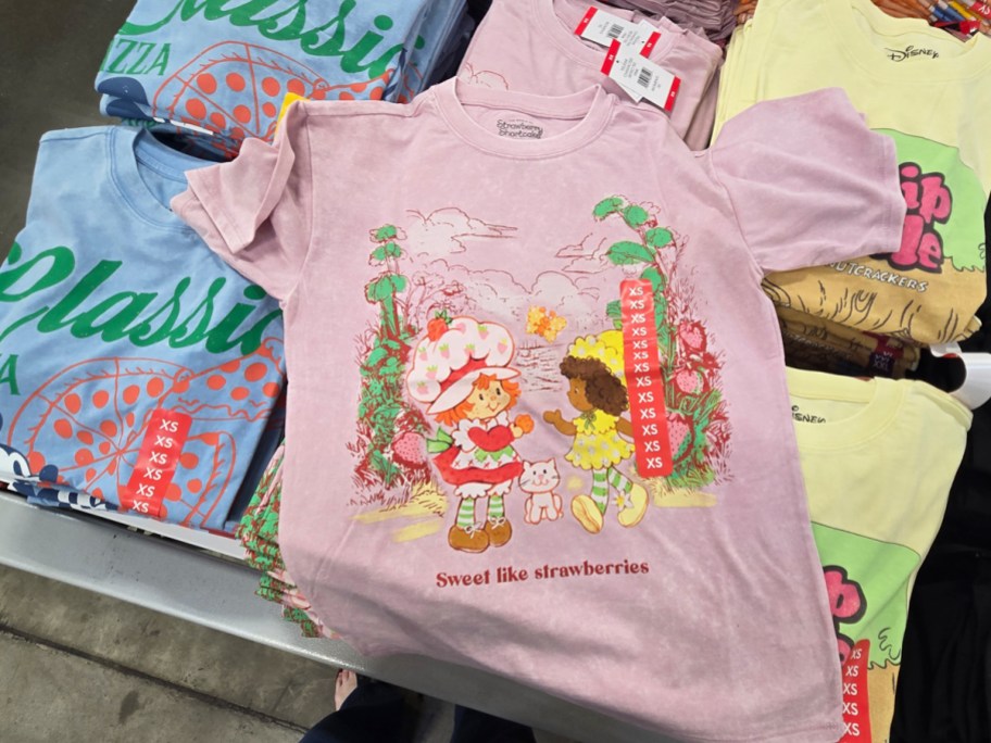 strawberry shortcake graphic tee on top of other folded tees