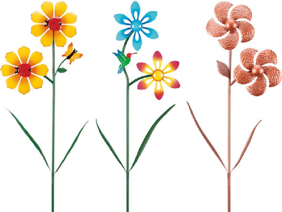 Three colorful garden stakes with pinwheel flowers. Left: yellow with a butterfly, center: blue and pink with a hummingbird, right: copper spirals.