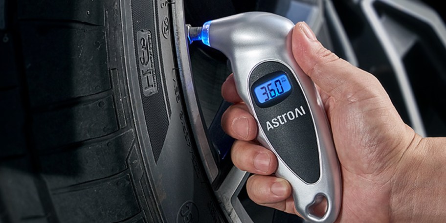 hand using tire pressure guage on tire 