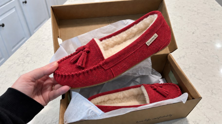 hand holding a red suede slip on shoe