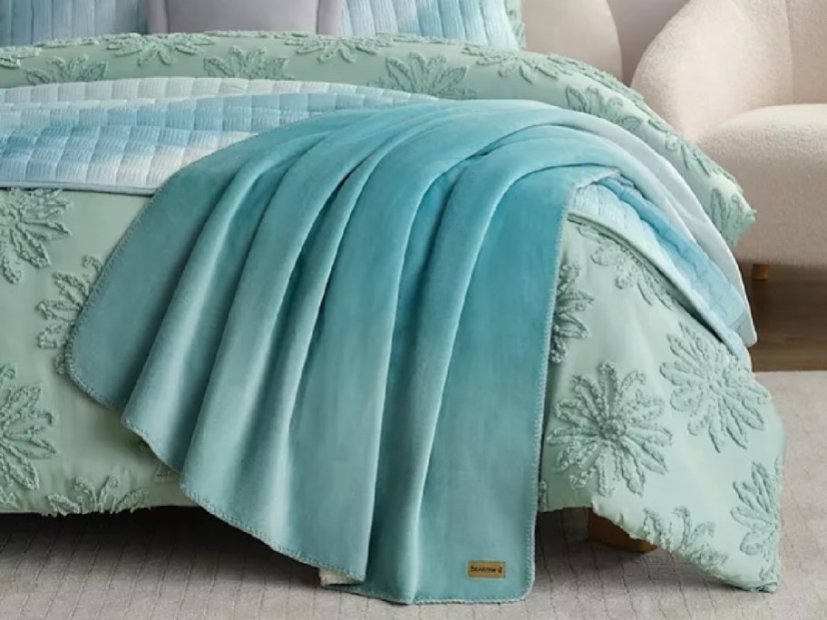 green blanket on a bed with green bedding