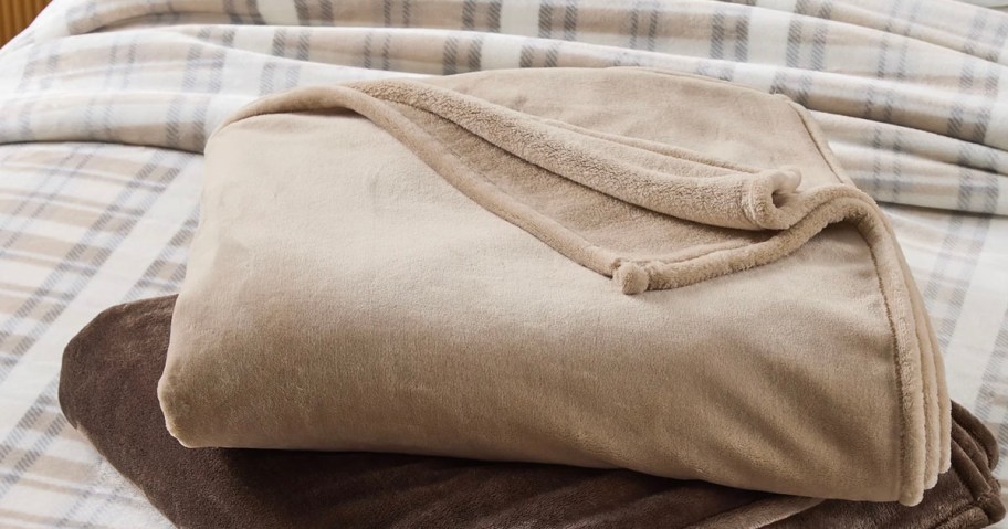 tan folded blanket on bed 