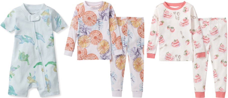 Burt's Bees Baby clothing items: a light blue dinosaur-print short-sleeve romper, a white and orange umbrella-print two-piece pajama set, and a white strawberry cake-print two-piece pajama set.