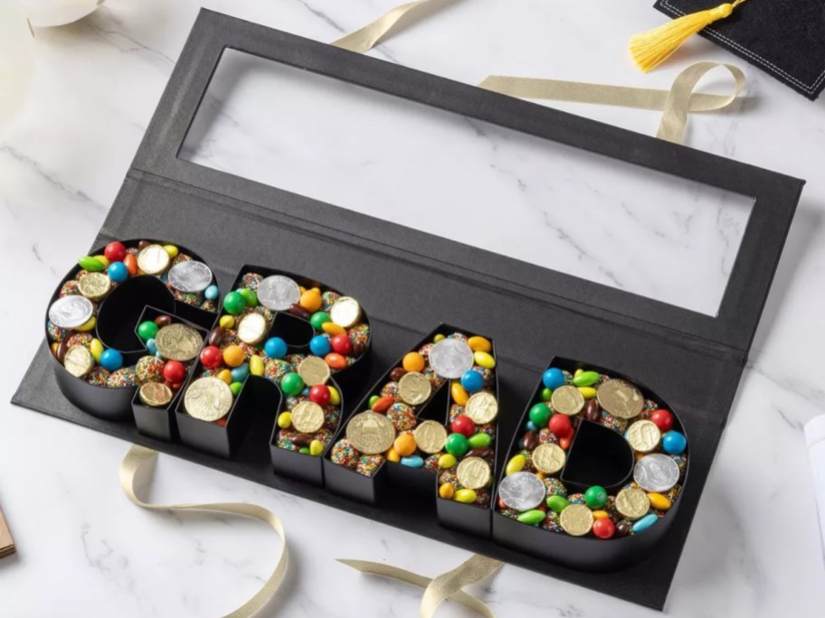 a snackle box with GRAD filled with candy and money