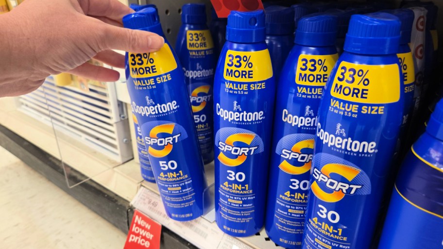hand pulling a can of sunscreen off a shelf full of coppertone sunscreens
