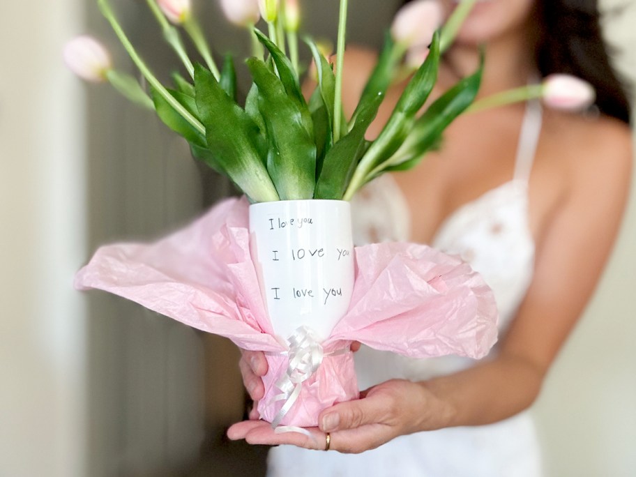 woman holding white i love you tumbler with flowers inside 
