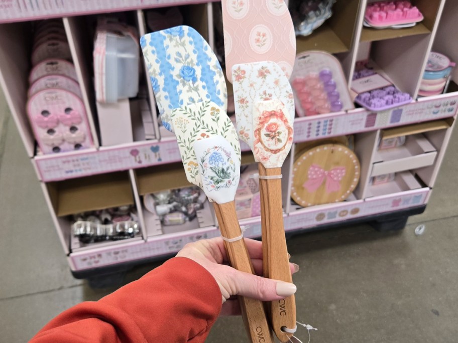 hand holding spatulas with florals and bows 