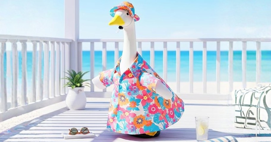 a porch goose in a floral Aloha style shirt and hat on a porch by the beach