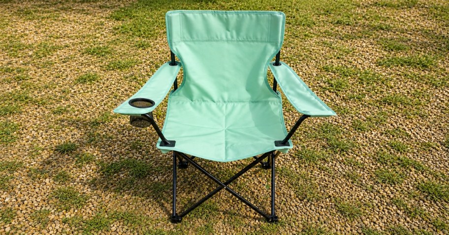 a green champing chair in a gravel and grass lot