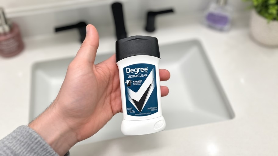man's hand holding a stick of deodorant