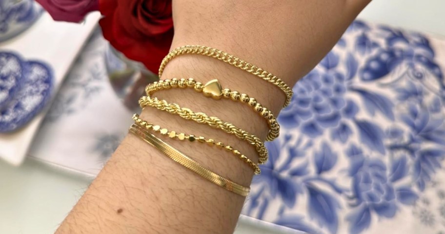 a woman's wrist wearing a gold-toned bracelet stack