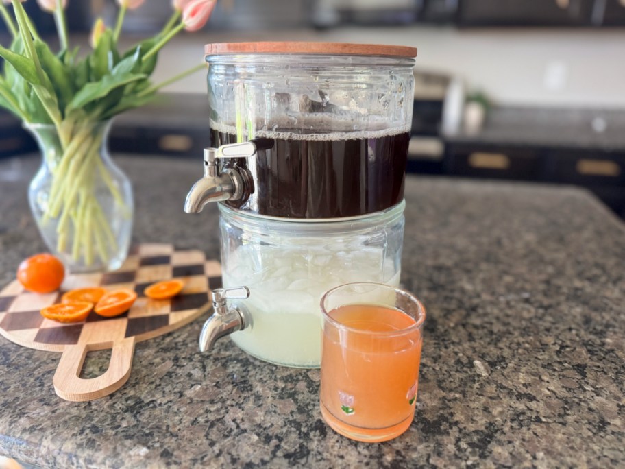 stacked drink dispenser on a counter near a filled glass