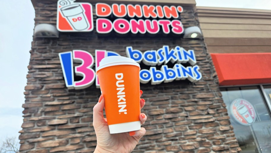 hand holding up a dunkin coffee cup