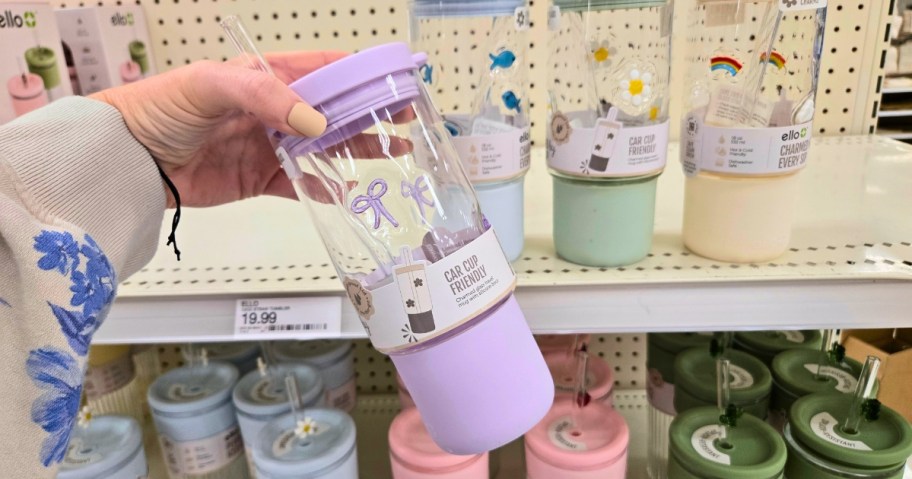 hand holding a purple and clear glass tumbler with bow designs on it
