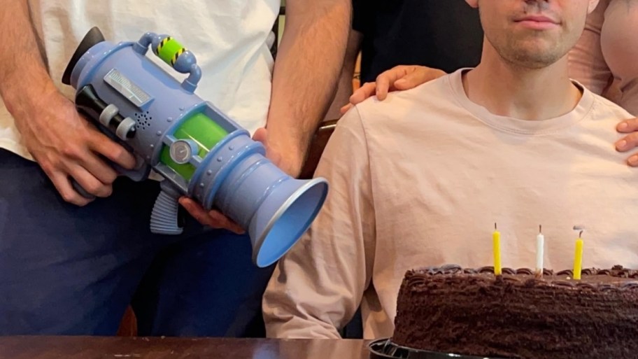 guy pointing a fart blaster at another guys bday cake