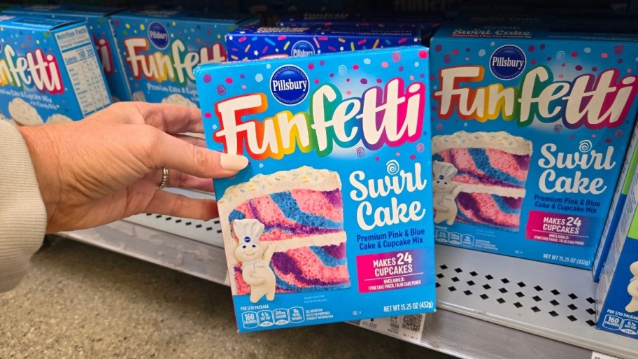 a womans hand holding a box of cake mix