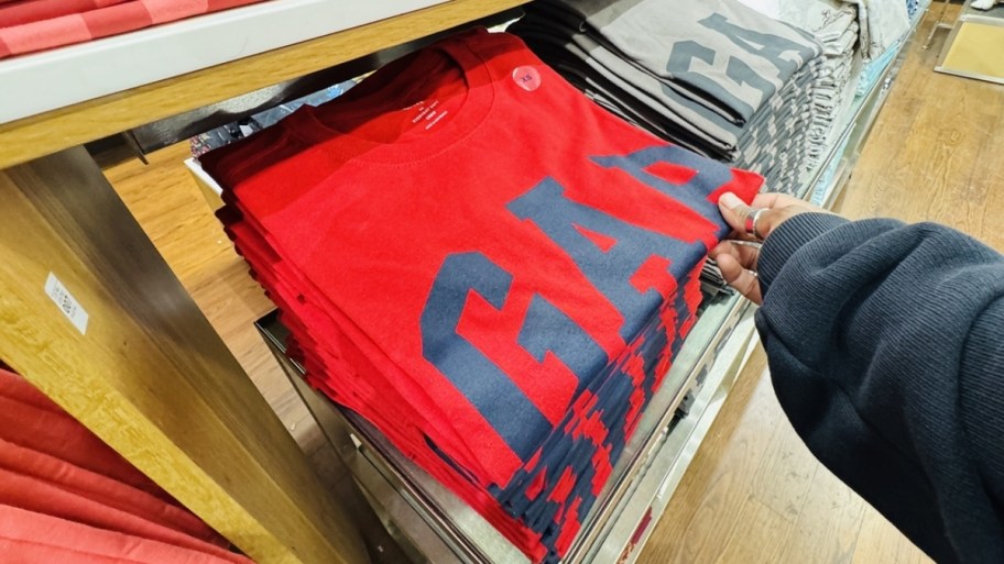 a woman grabbing a folded red gap top