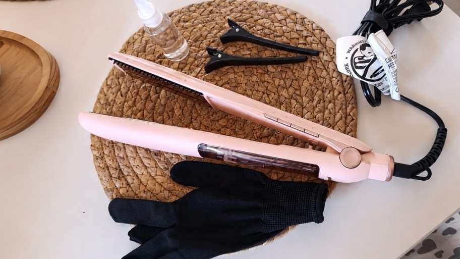 a pink steam hair straightener shown with glove and hair clips