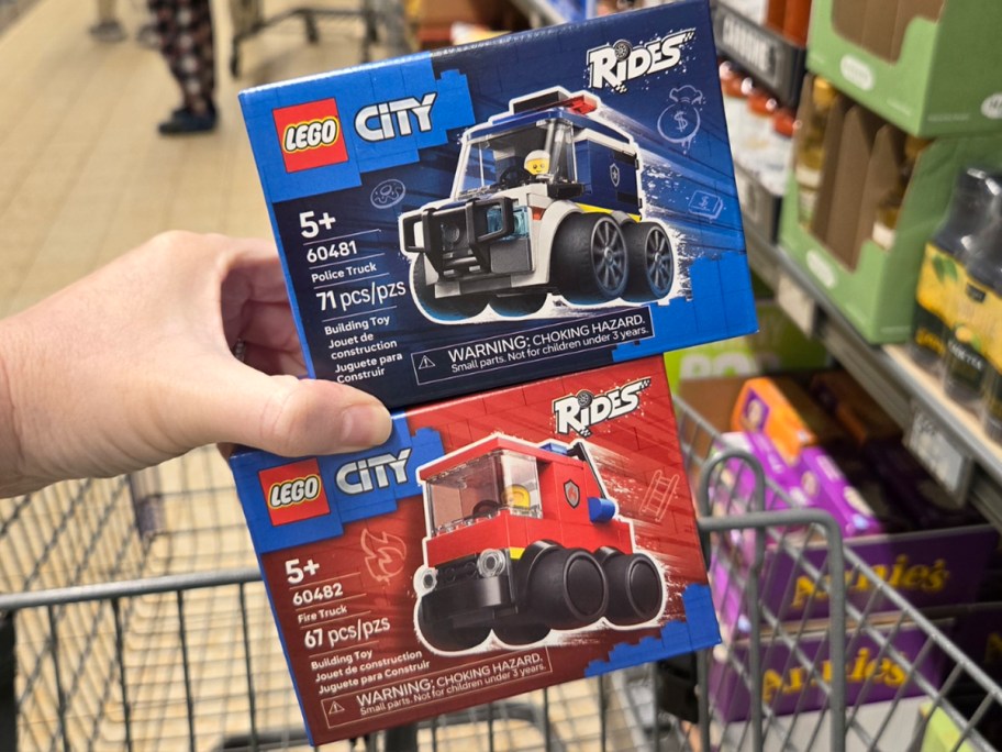 hand holding lego city police car and fire truck