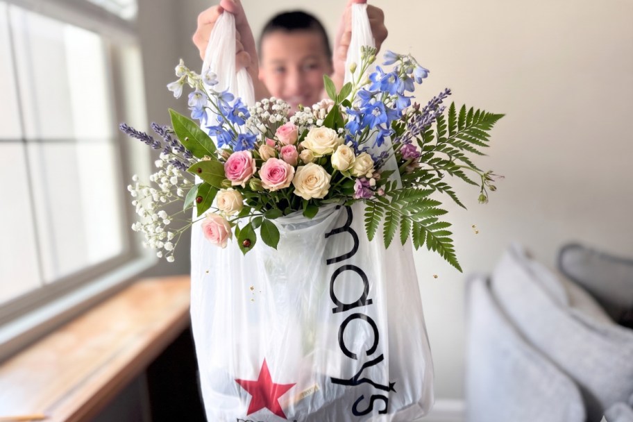 boy holding plastic bag with flowers sticking out