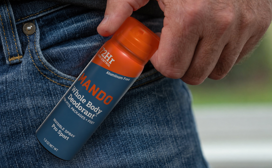 hand holding Mando spray deodorant 1 oz travel size next to jeans pocket