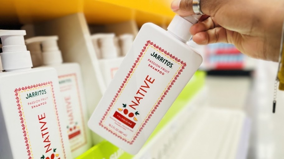 woamns hand holding a bottle of native shampoo