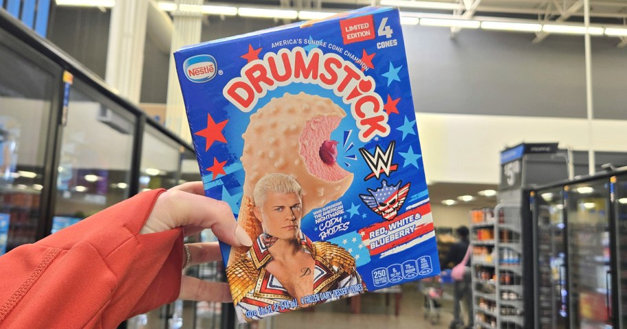 A box of limited edition Drumstick ice cream cones is held up in a store. The packaging features red, white, and blue stars and a wrestling theme.