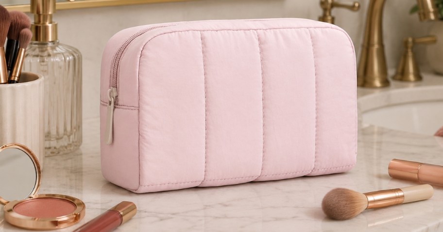 a pink puffy makeup bag on a bathroom counter