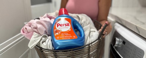 bottle of persil laundry detergent on a basket of clothes being held by a woman