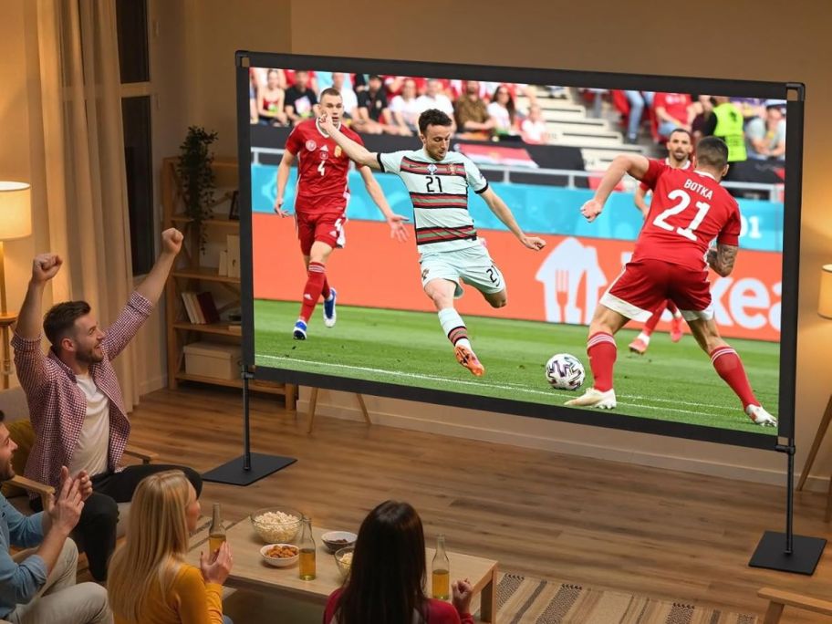 family watching soccer on a portable projector screen