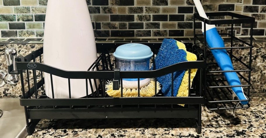black metal sink caddy shown with dish cleaning items