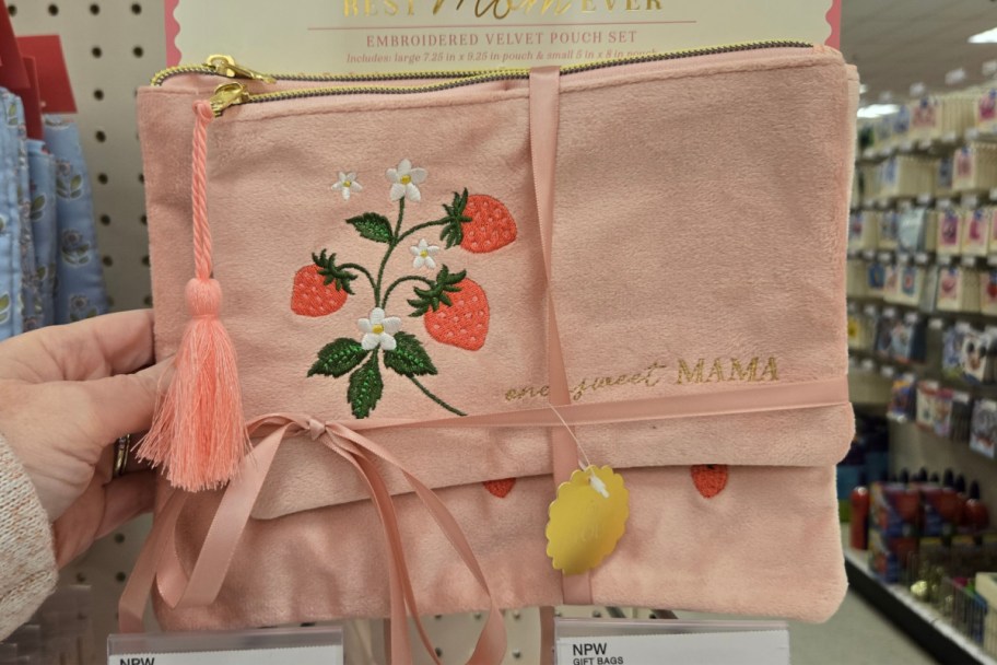 hand holding two pink pouches with strawberries on them