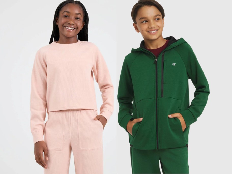 Two kids, one wearing a light pink tracksuit, the other a green hoodie and pants, both smiling against a plain background.