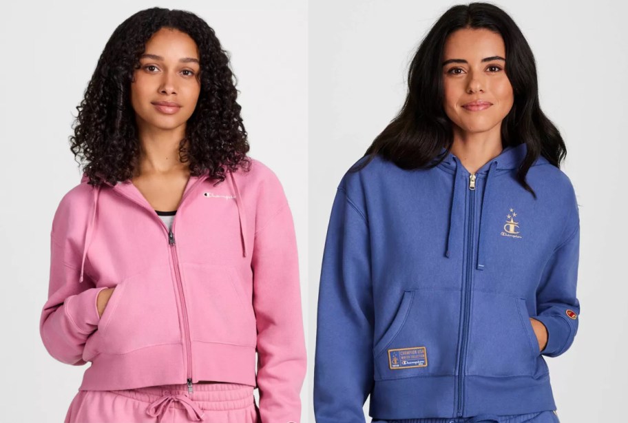 Two women stand side by side, both in hoodies. The left wears pink, the right blue with logo details.