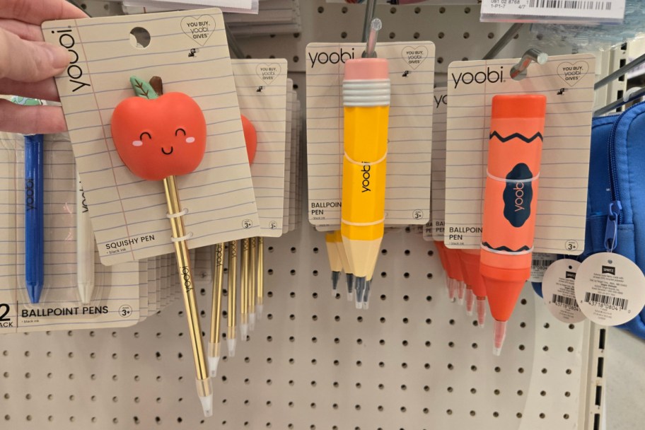 apple, pencil, and crayon pens hanging on store shelf