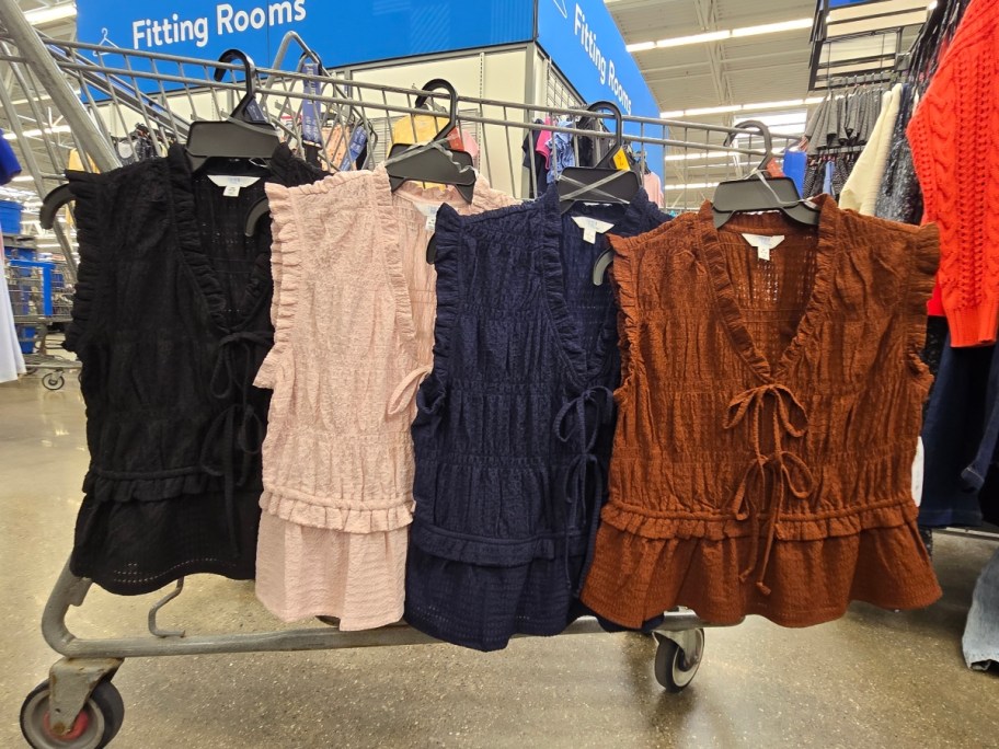 4 sleeveless shirts hanging on a Walmart shopping cart