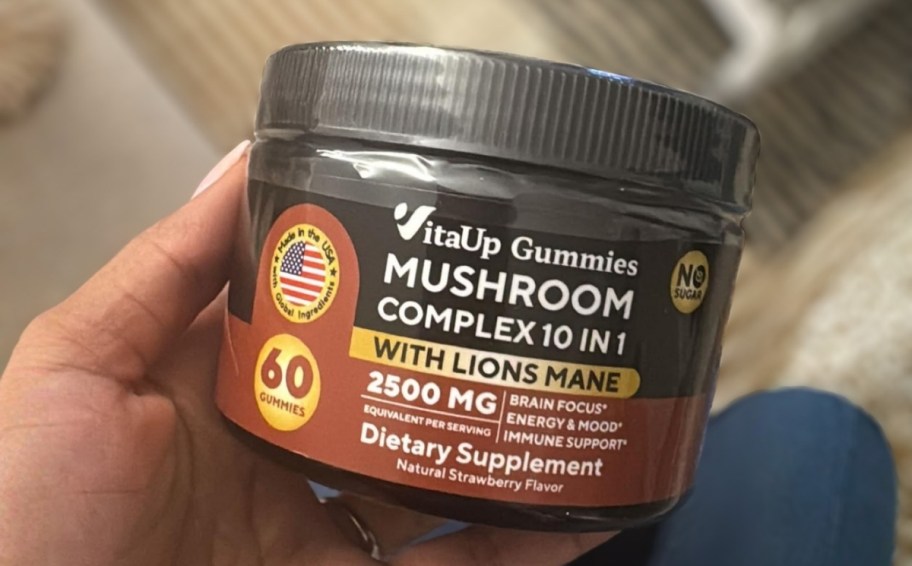 womans hand holding a jar of mushroom gummy supplements