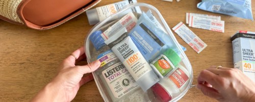 hand grabbing clear pouch with hygiene, beauty, and more products