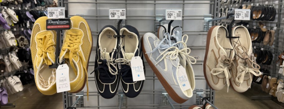 Four pairs of shoes are displayed on a store rack: yellow, black, light blue, and beige styles.