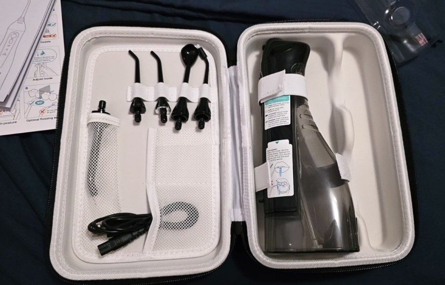 water flosser and included accessories in case on countertop